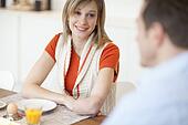 Young woman with amputee arm sitting at breakfast table, mid adult man